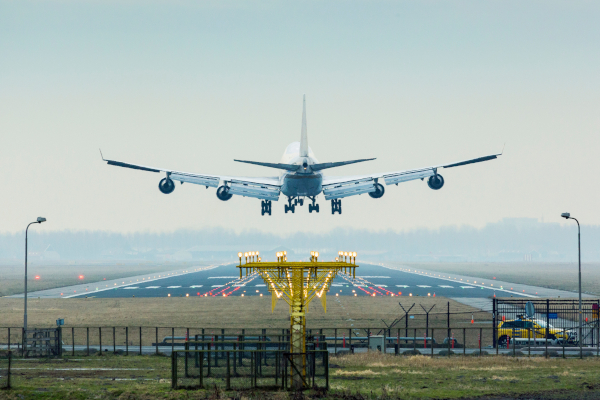 Airplane landing on runway with lights.