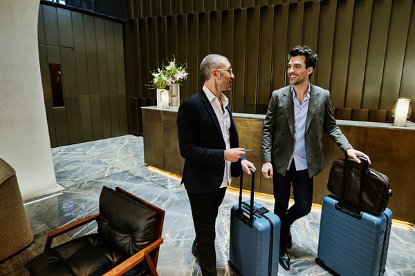 Deux hommes avec valises à la réception d'hôtel.