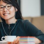 Smiling woman with earphones using a laptop.