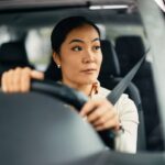 Woman driving car attentively.